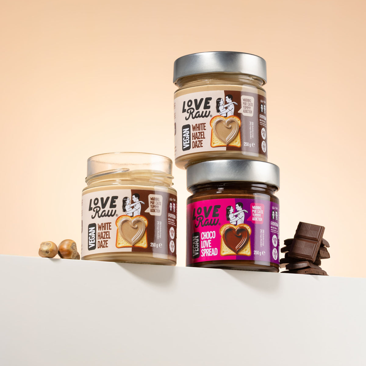 Three jars of LovRaw spreads on a white surface with a beige background