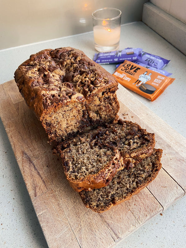 Our delicious banana bread cut into slices and oozing chocolate onto a wooden chopping board.