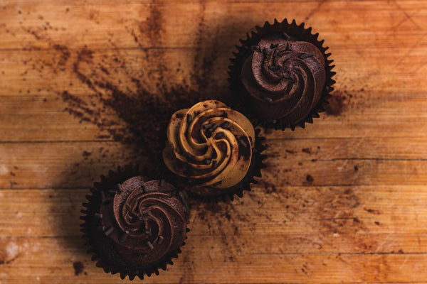 three vegan chocolate cupcakes in a row, with vegan chocolate icing